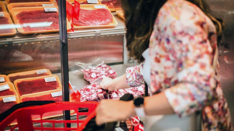 mulher a comprar carne no supermercado